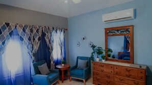 Una habitació amb dos seients blaus, un taulell de fusta, una taula rodona petita i un mirall a la paret.