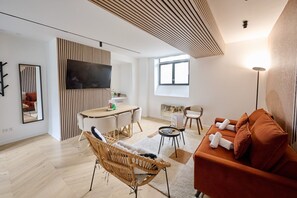 Un salon moderne avec un canapé, une table à manger et un téléviseur fixé au mur.