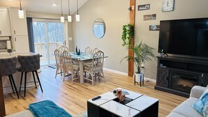 Un salon moderne comprenant un coin repas, une cheminée et un téléviseur.