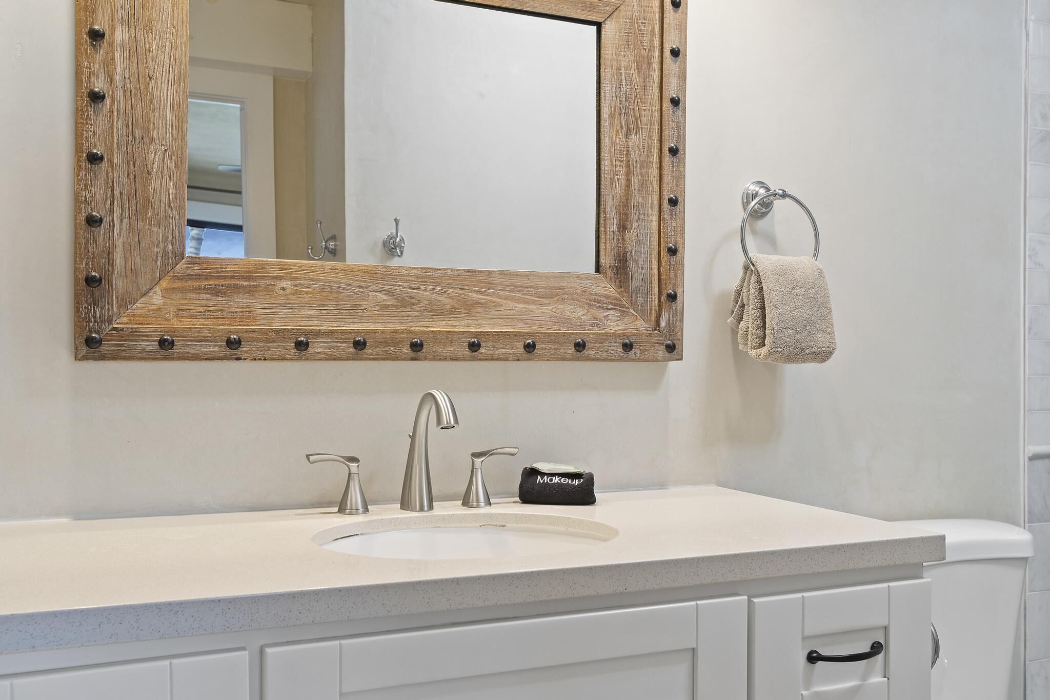 A bathroom with a wooden-framed mirror, a white sink, and a towel rack.