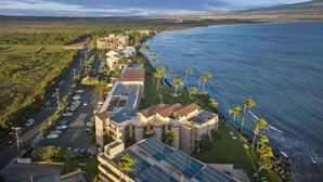 Un hôtel situé sur la côte, composé de plusieurs bâtiments, doté d’un parking et offrant une vue sur l’océan.