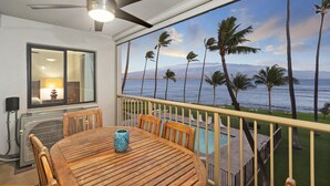 Un balcon avec vue sur l’océan, une piscine et un coin repas avec une table et des chaises.