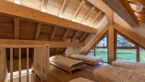 Un dormitorio abuhardinado con techos altos, vigas de madera, dos camas individuales y una cuna de madera.