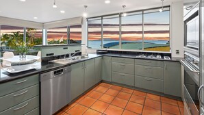 Cozinha moderna com uma janela ampla que oferece uma vista panorâmica de campos e um pôr do sol.