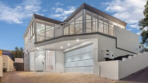Uma casa moderna de dois andares com grandes janelas, uma garagem e entrada de automóveis em tijolo.