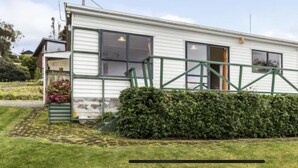 Una casa de un piso con una escalera metálica verde que lleva a la puerta principal.