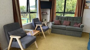 Una sala acogedora con un sofá gris, dos sillones y una pequeña mesita de madera.