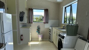 Cocina compacta con lavadora, una silla y ventana con vistas.