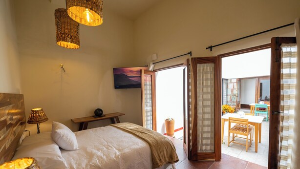 Un dormitorio con cama, lámpara de noche y vistas a un balcón con mesa y sillas.