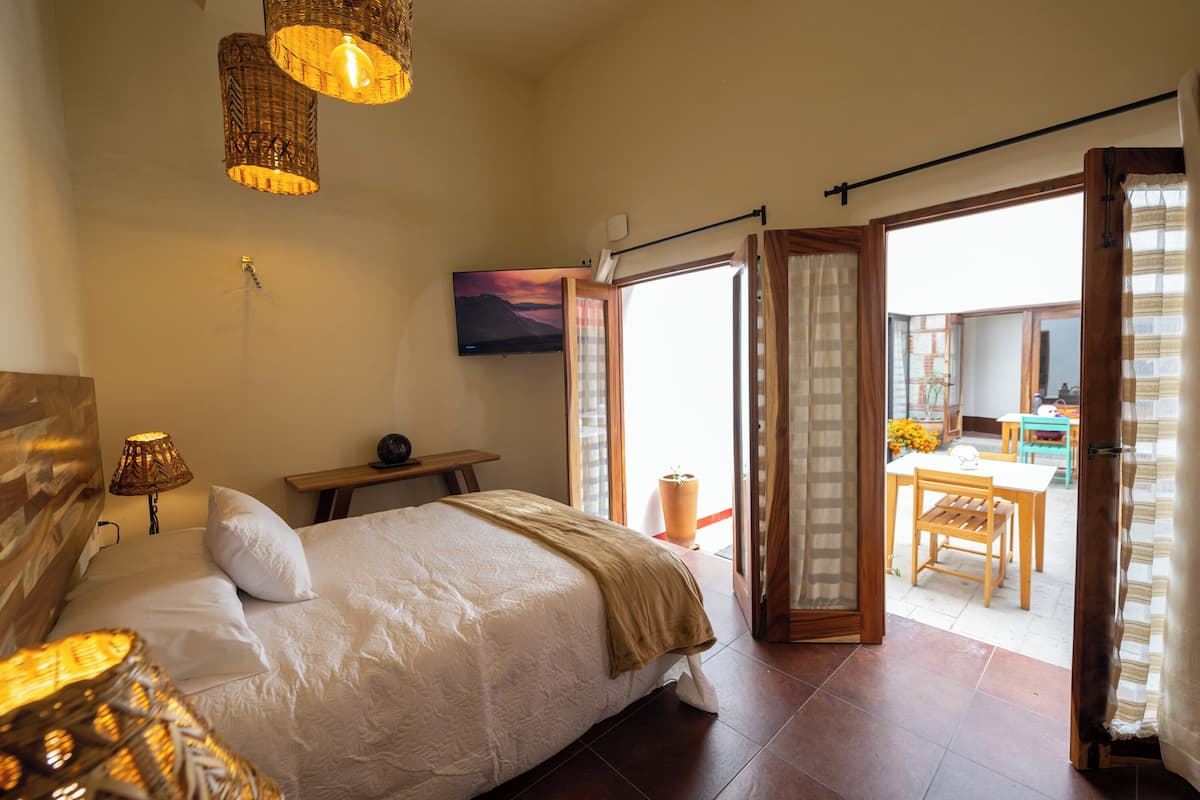 Un dormitorio con cama, lámpara de noche y vistas a un balcón con mesa y sillas.