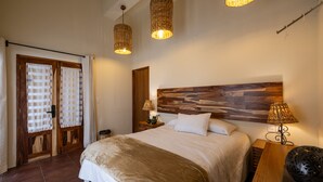 Un dormitorio con una cama grande, cabecera de madera, dos lámparas de noche y un mesita de noche de madera.
