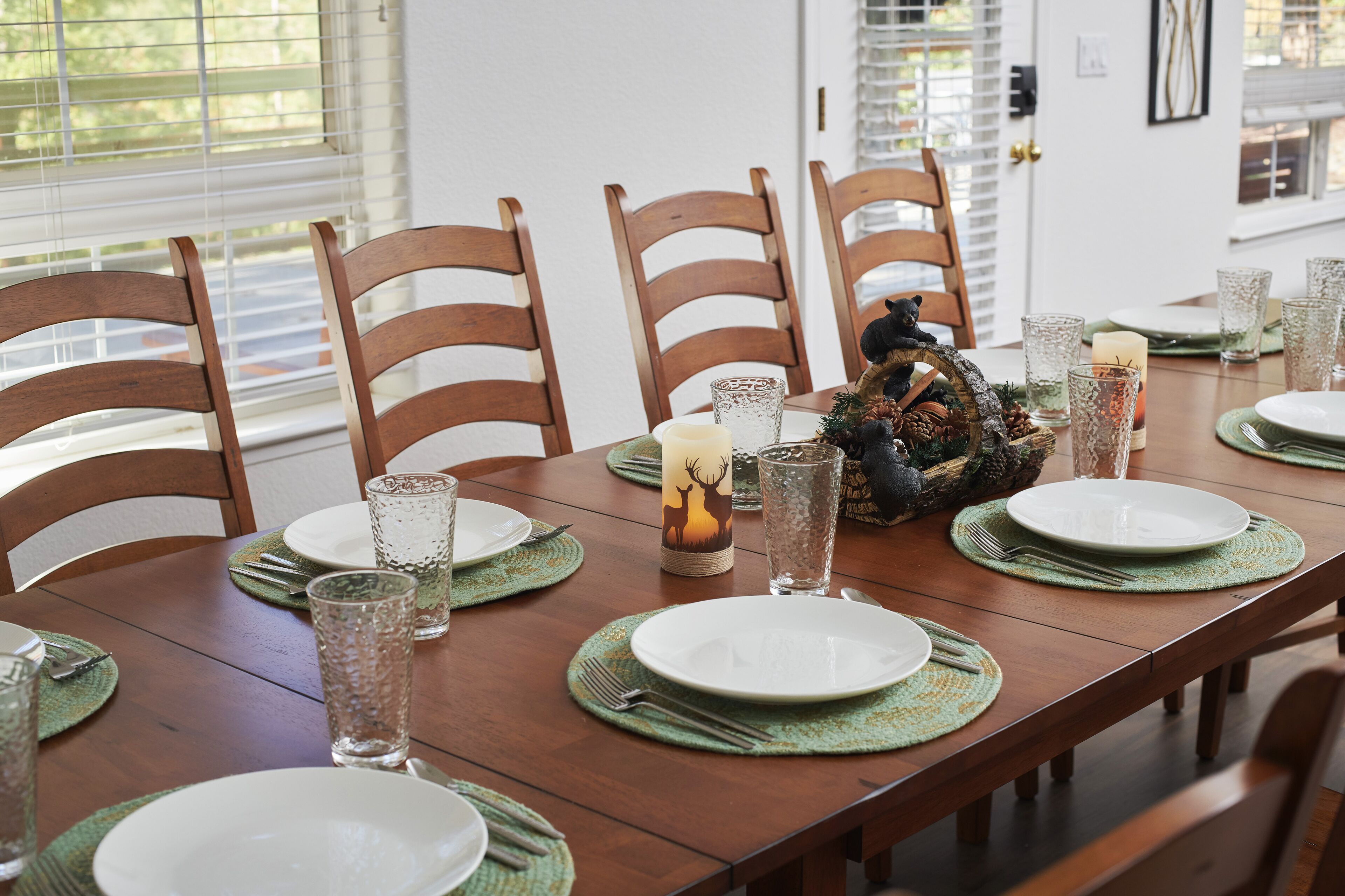 A dining table set with plates, glasses, and a candle centerpiece.