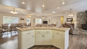 A spacious living area with a large kitchen island, dining table, and seating. - Scenic Mountain Views w/ Game Room, Pool & Hottubs (Oakhurst)