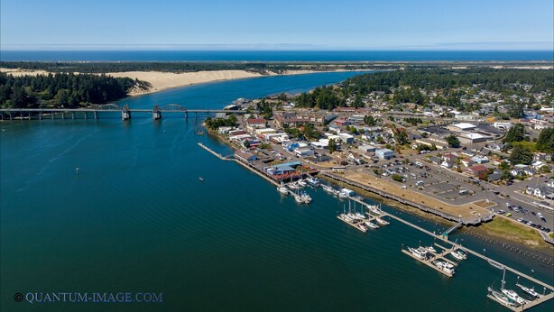 An aerial view of a coastal town with a marina, a bridge, and a beach.