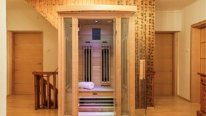 A sauna with a wooden interior, glass doors, and a towel on the bench.