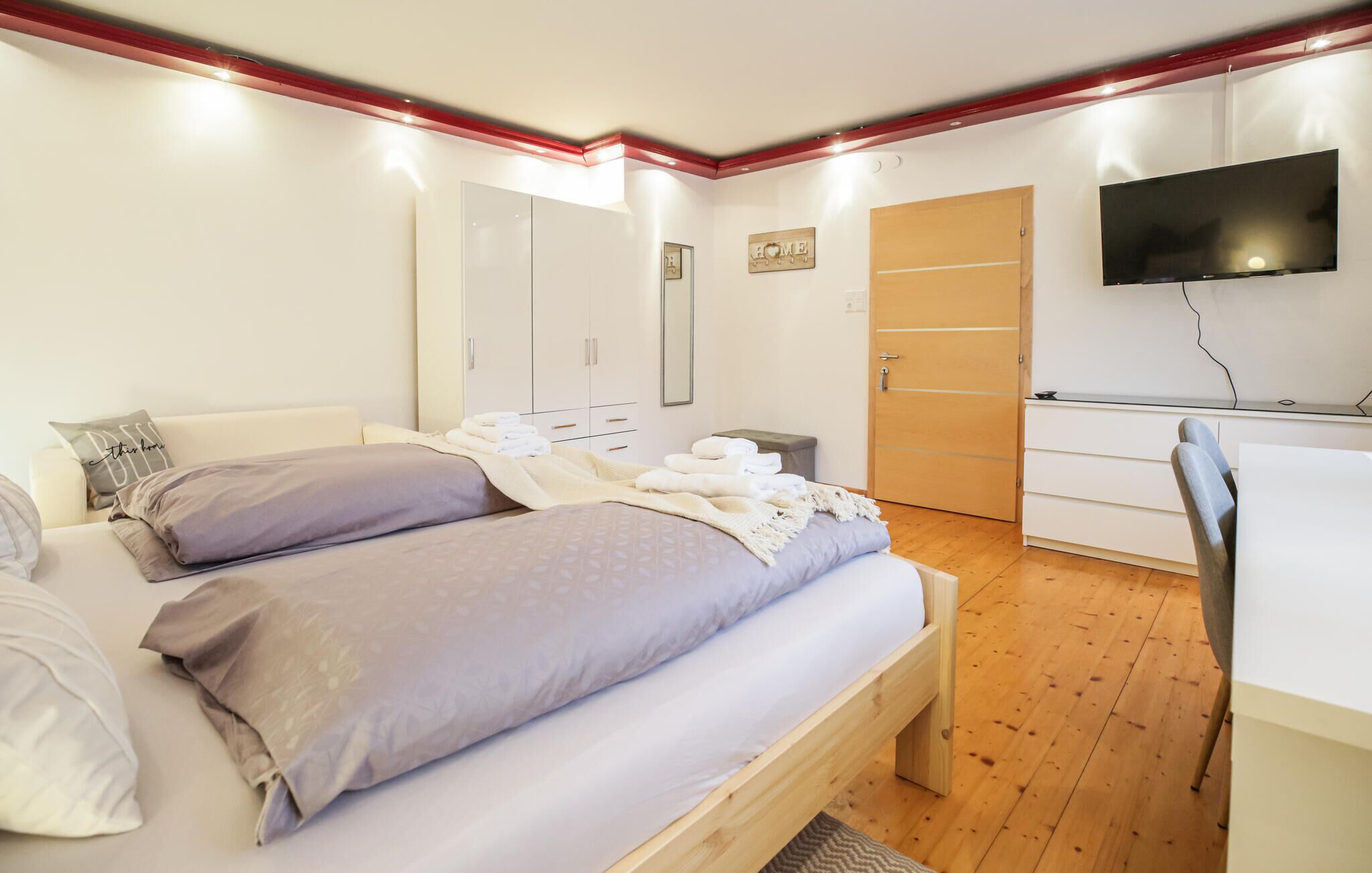 A bedroom with a bed, a desk, a TV, and a wardrobe.