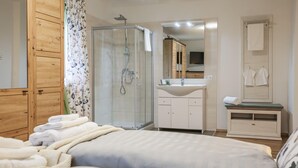 A bedroom with a bed, a shower, a sink, and a mirror.