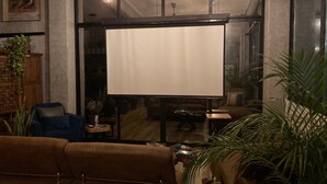 Un salon confortable avec une grande fenêtre, un canapé, une table basse et un écran de télévision.