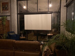 Un accogliente soggiorno con un'ampia finestra, un divano, un tavolino da caffè e uno schermo televisivo.