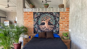 Une chambre à coucher moderne avec un grand lit, une fresque murale représentant un arbre décoratif et plusieurs plantes en pot.