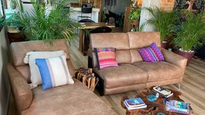 Un salon chaleureux avec deux canapés en cuir marron, une table basse et divers coussins décoratifs.