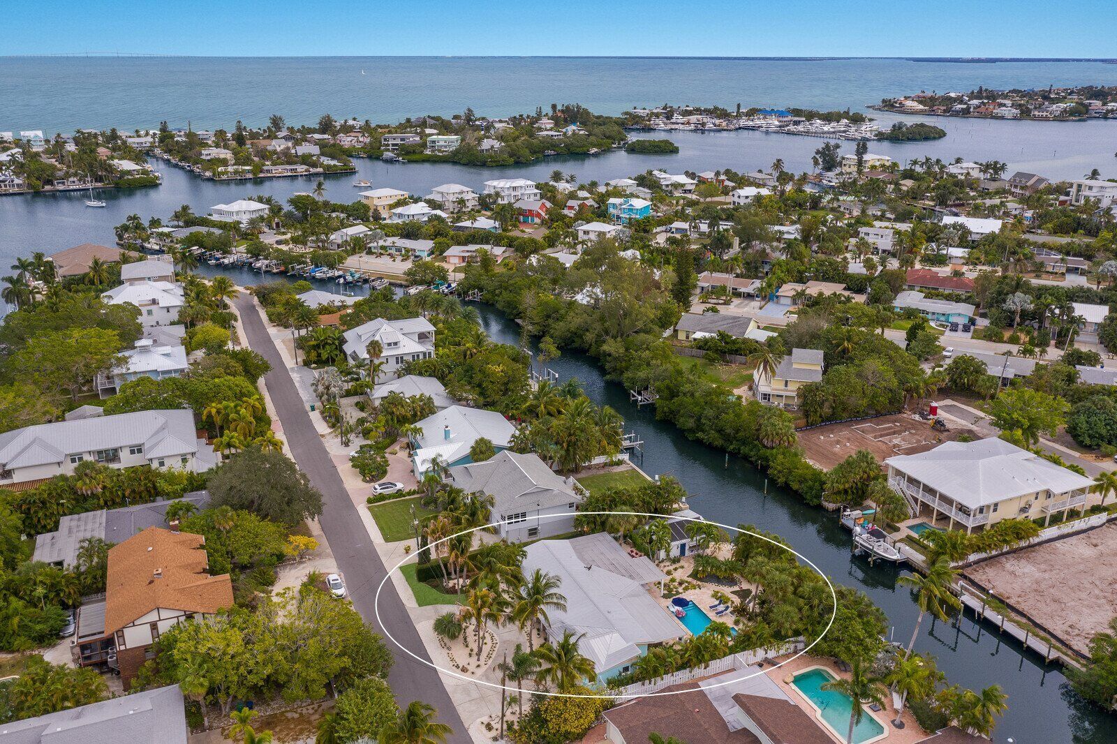 Vista aérea de una zona residencial costera con casas, un puerto deportivo y una vista despejada del océano.