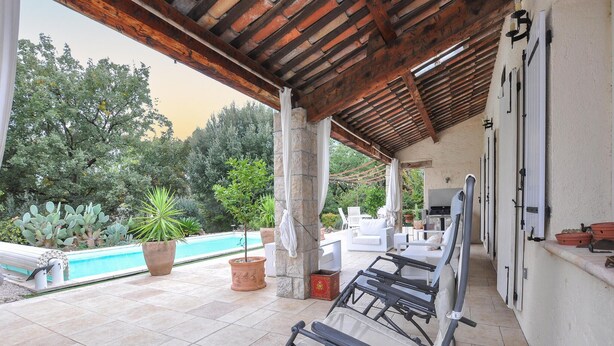 Un espace extérieur abrité comprenant une piscine, des chaises longues et un barbecue.