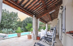 Un espace extérieur abrité comprenant une piscine, des chaises longues et un barbecue.
