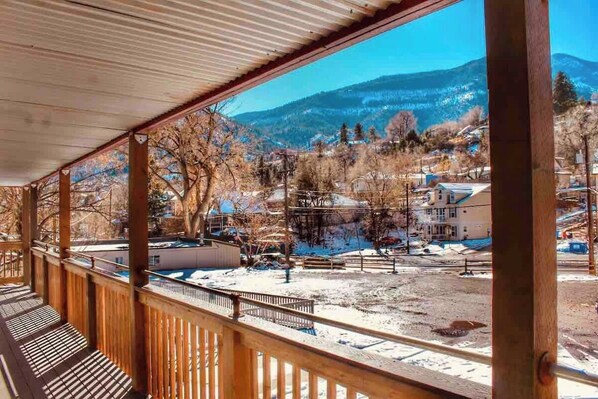 A covered outdoor area with a view of a snowy landscape and buildings in the distance.