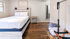 Un dormitorio con cama, mesita de noche, lámpara y vistas al exterior.