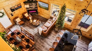 Een knus houten interieur met een open haard, een eethoek en een kerstboom.