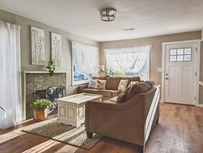 Una sala de estar con chimenea, un sofá, una mesa de centro y una puerta.
