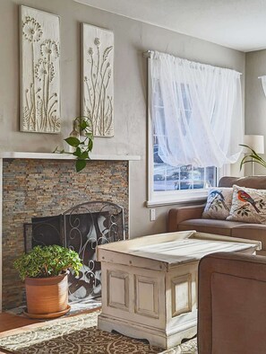 Una sala de estar con chimenea, un sofá, una mesa de centro y decoración en la pared.
