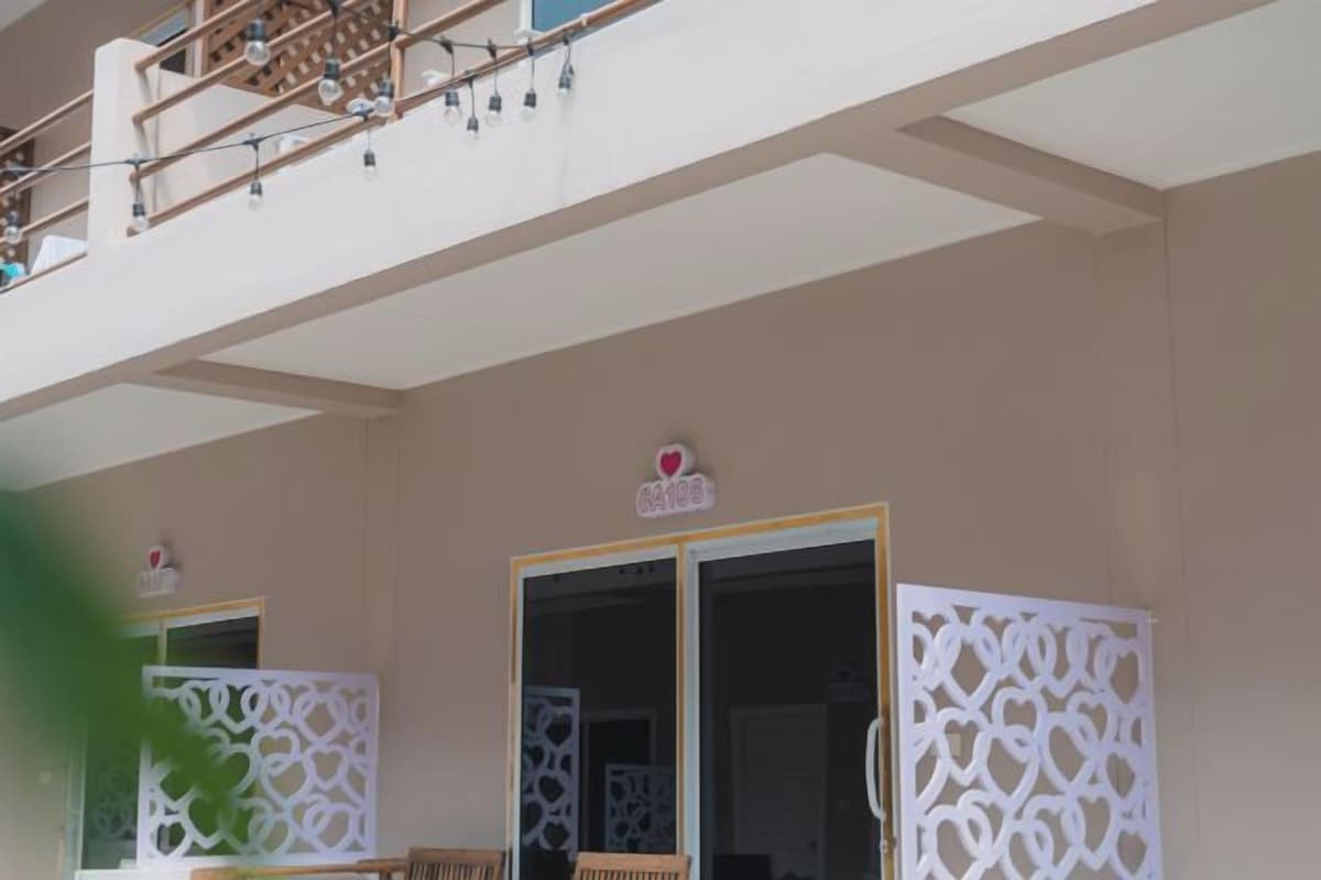 Une chambre d’hôtel avec un balcon, une porte-fenêtre coulissante et des panneaux décoratifs blancs.