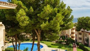 Una piscina rodeada de árboles y un edificio con balcones.