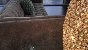 Una sala de estar moderna con un sofá, una lámpara decorativa y vistas al exterior a través de grandes ventanales.