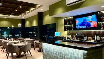 Un área de bar moderna con una pantalla grande de televisión, una barra y asientos.