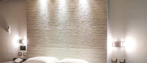 Un dormitorio moderno con cama, mesitas de noche y una pared con textura.