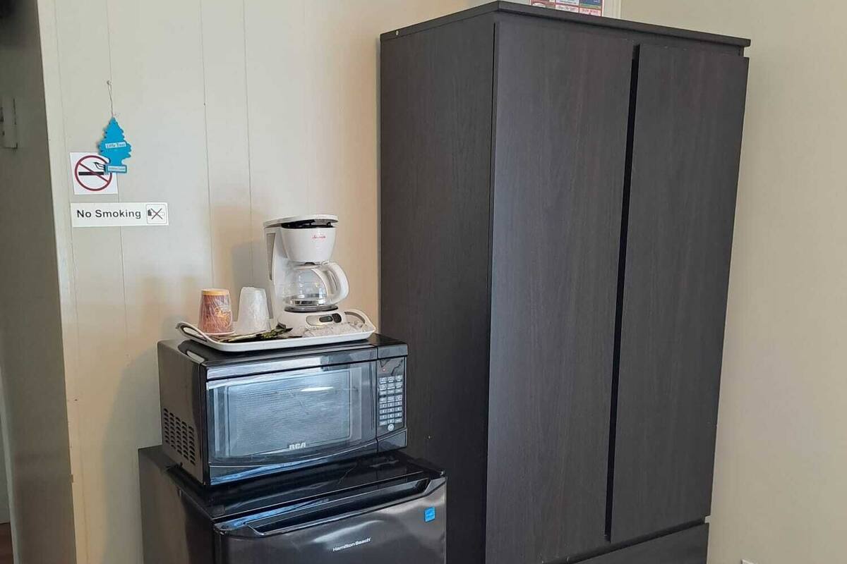 A compact kitchenette with a refrigerator, microwave, and coffee maker.