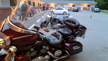 A motorcycle parked in front of a building with a ramp leading to the entrance.