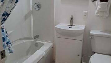 A bathroom with a bathtub, a sink, a toilet, and a mirror.