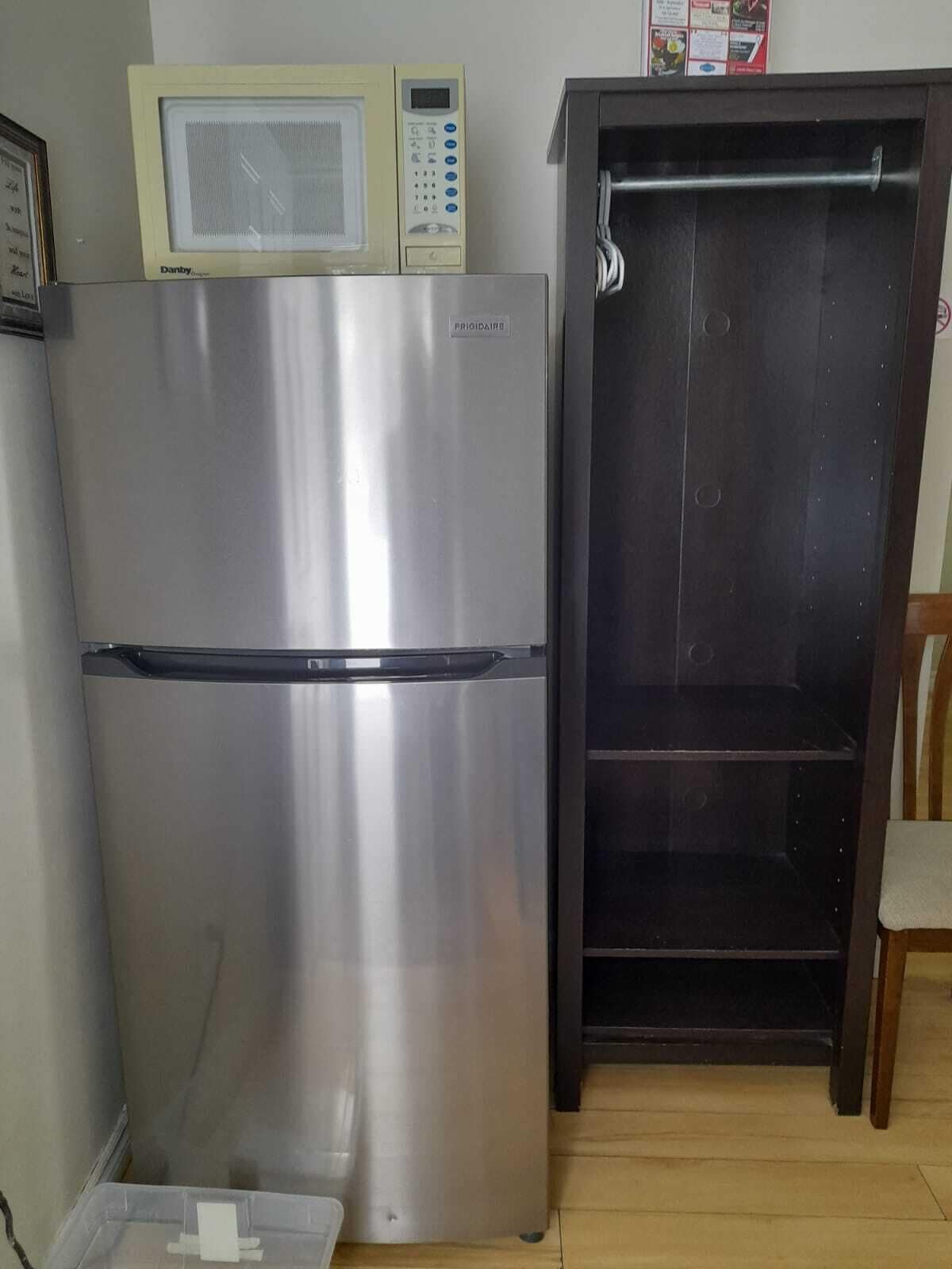 A stainless steel refrigerator with a digital display and a microwave above it.