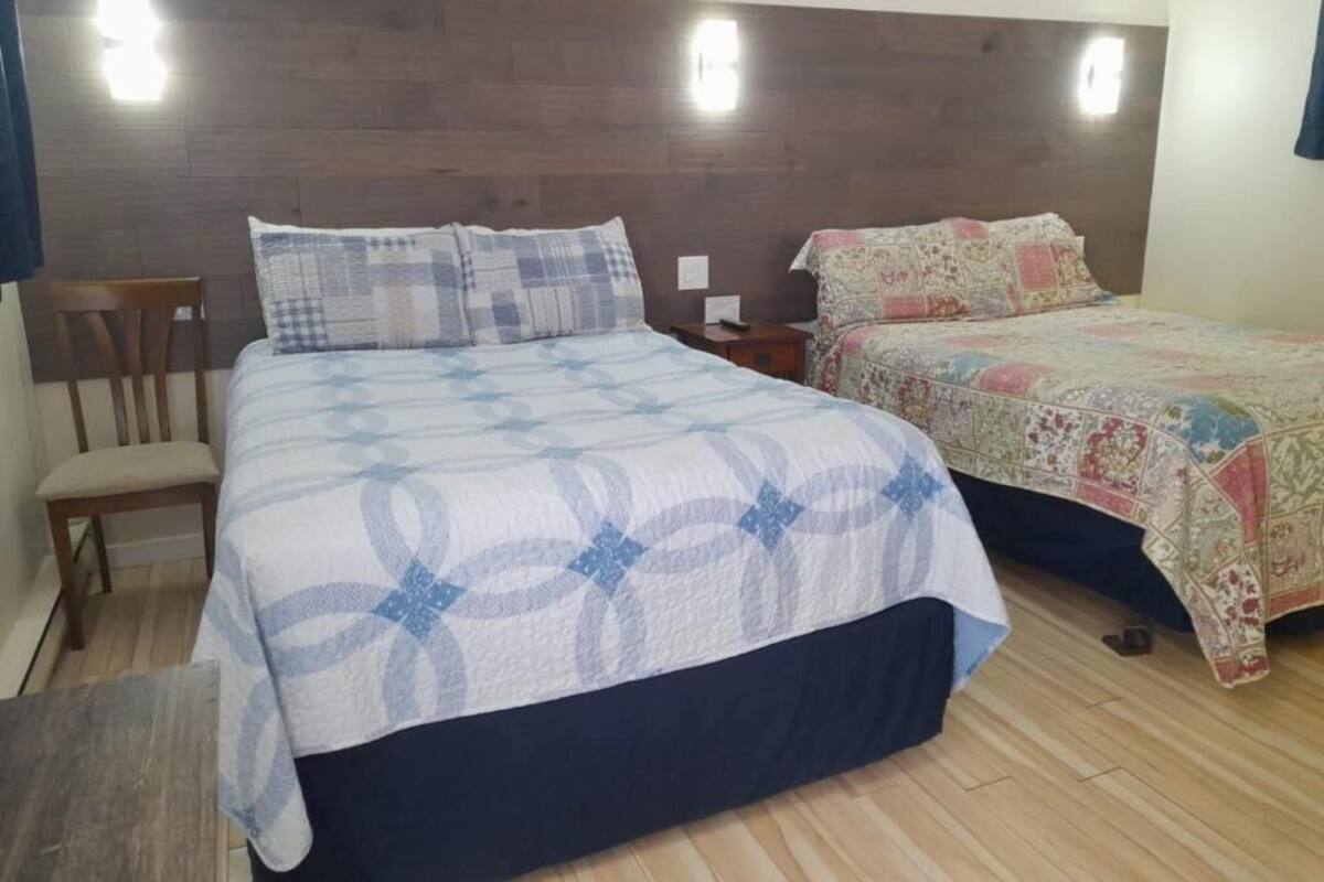 A bedroom with two beds, a wooden headboard, and a nightstand.