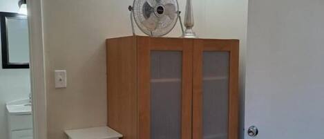 Una habitación con un armario de madera, una estantería blanca y una puerta.