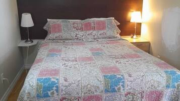 A bed with a quilt, two bedside lamps, and a dark headboard.