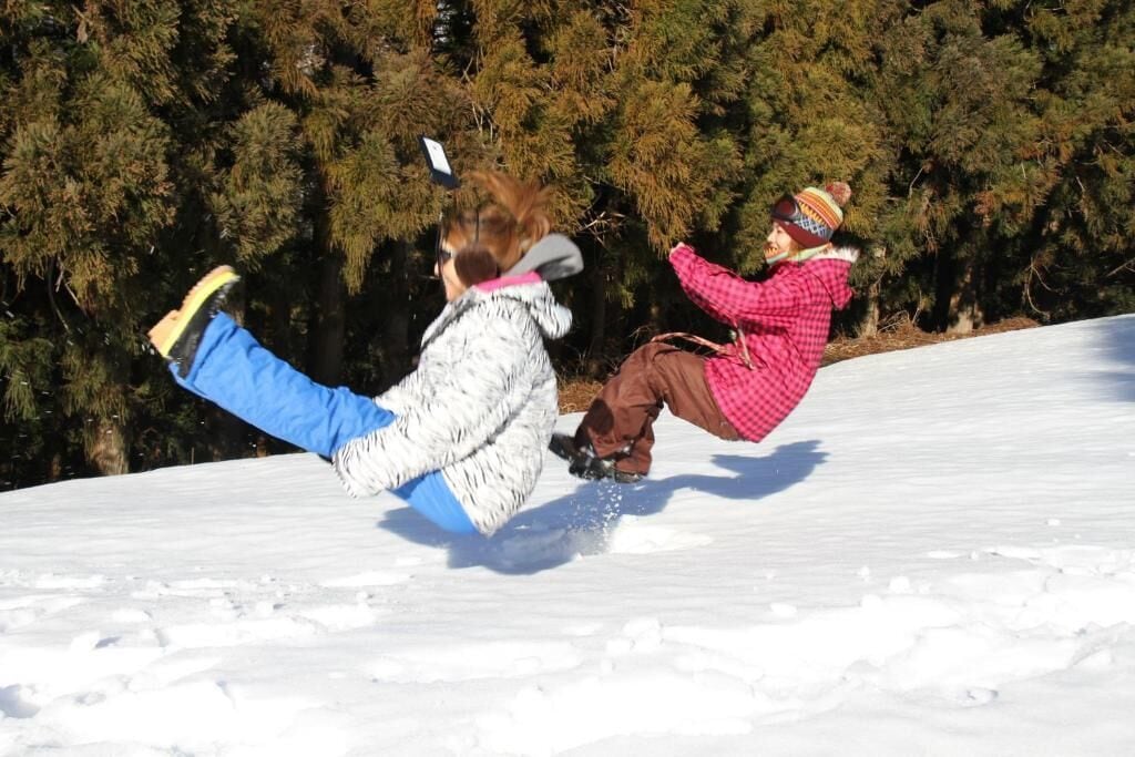 Two people sliding down a snowy slope.
