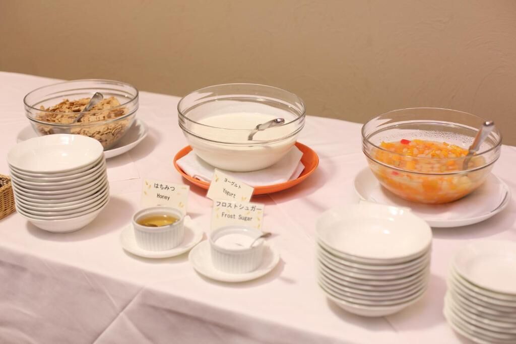 A buffet table with bowls of yogurt, honey, and fruit salad.