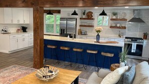 Een moderne keuken met een centraal eiland, barstoelen en een zithoek met een houten tafel en bank.