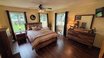 Un dormitorio con cama, cómoda, mesitas de noche y ventilador de techo.