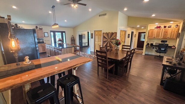 A spacious kitchen with wooden cabinets, a dining area with a large wooden table, and a bar with stools. - Rusty’s Getaway is a rustic/modern handicap accessible, family friendly space.  (Findlay)